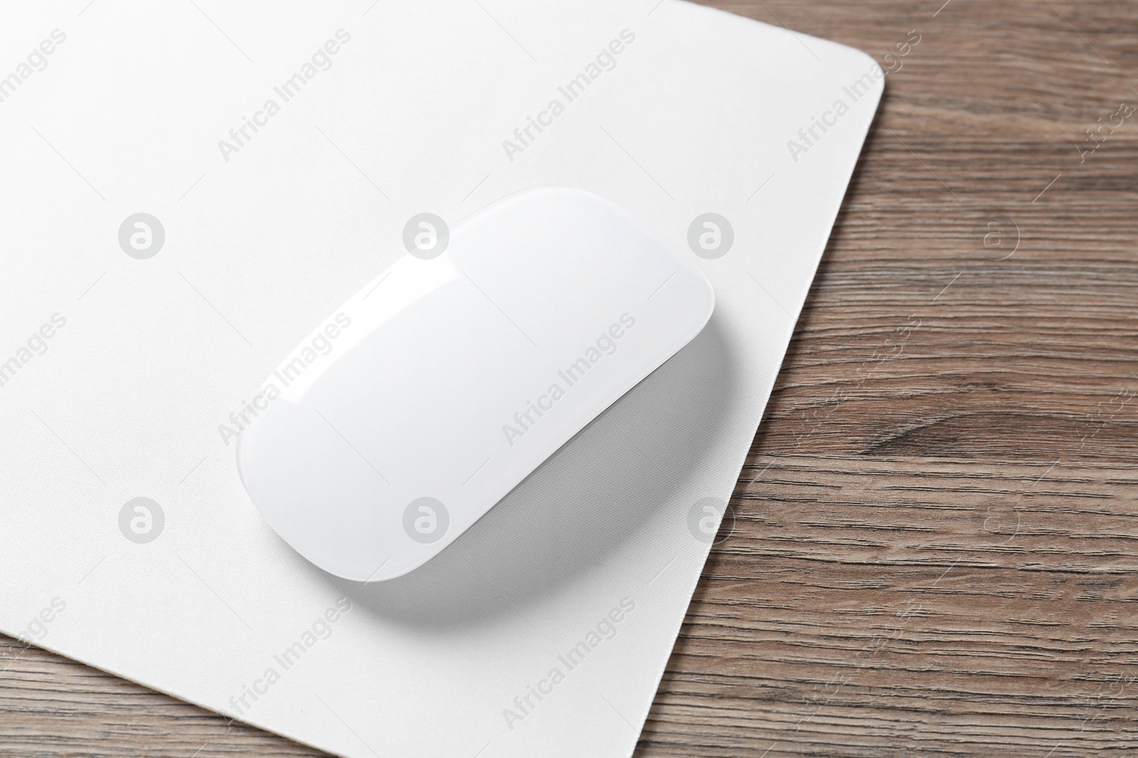 Photo of Computer mouse with mousepad on wooden desk, closeup