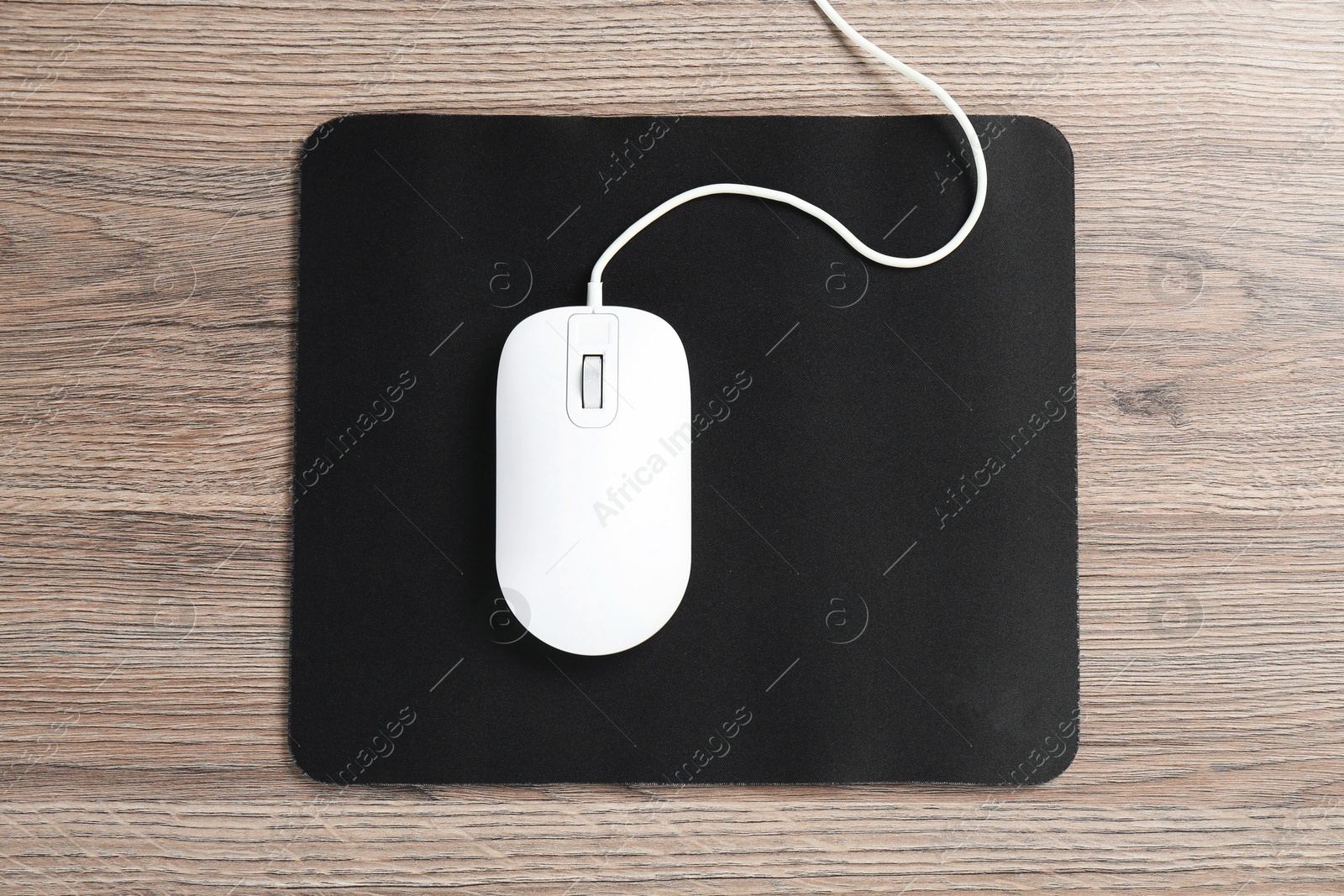 Photo of Computer mouse with mousepad on wooden desk, top view