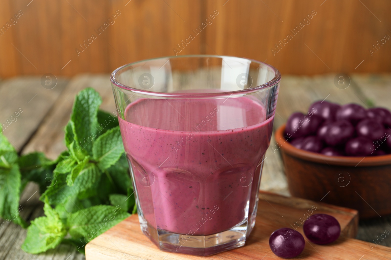 Photo of Tasty fresh acai juice in glass with berries and mint on table, closeup