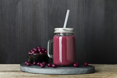 Photo of Tasty fresh acai juice in mason jar and berries on wooden table