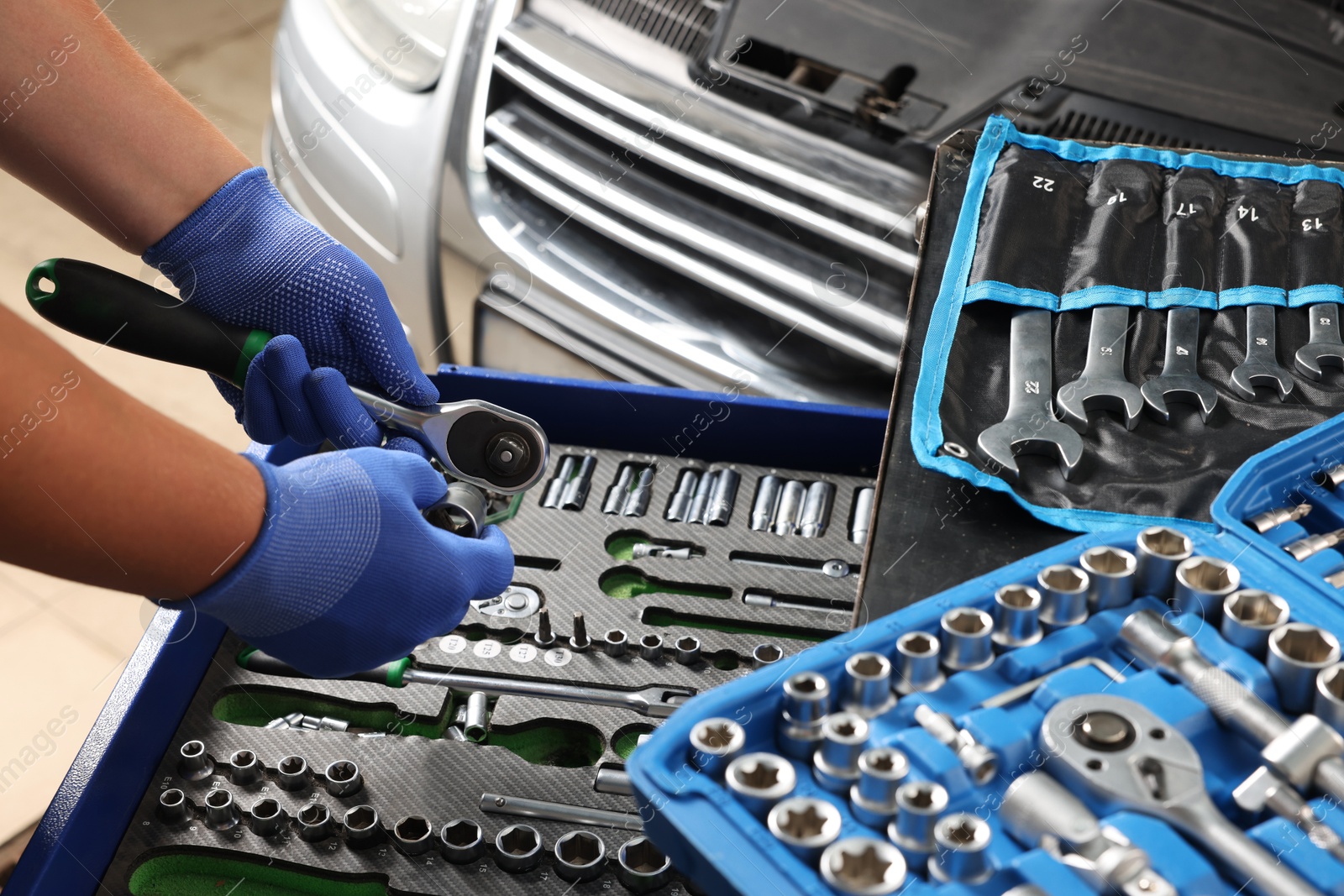 Photo of Auto mechanic with different tools at automobile repair shop, closeup