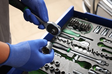 Auto mechanic with different tools at automobile repair shop, closeup