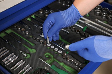 Auto mechanic with different tools at automobile repair shop, closeup