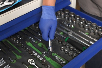 Auto mechanic with different tools at automobile repair shop, closeup