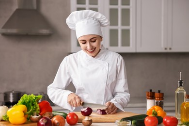 Photo of Professional chef cutting onion at table in kitchen