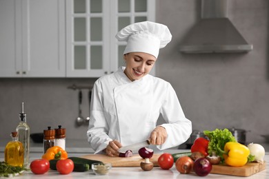 Photo of Professional chef cutting onion at table in kitchen