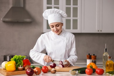 Professional chef cutting onion at table in kitchen