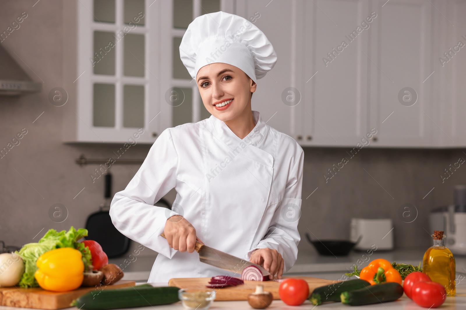 Photo of Professional chef cutting onion at table in kitchen