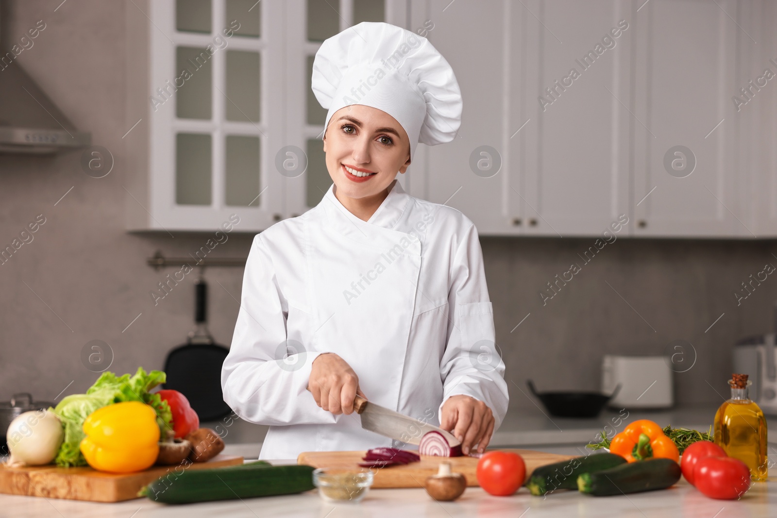 Photo of Professional chef cutting onion at table in kitchen