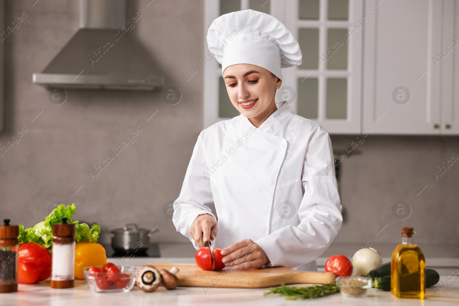 Photo of Professional chef cutting tomato at table in kitchen