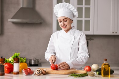 Professional chef cutting tomato at table in kitchen