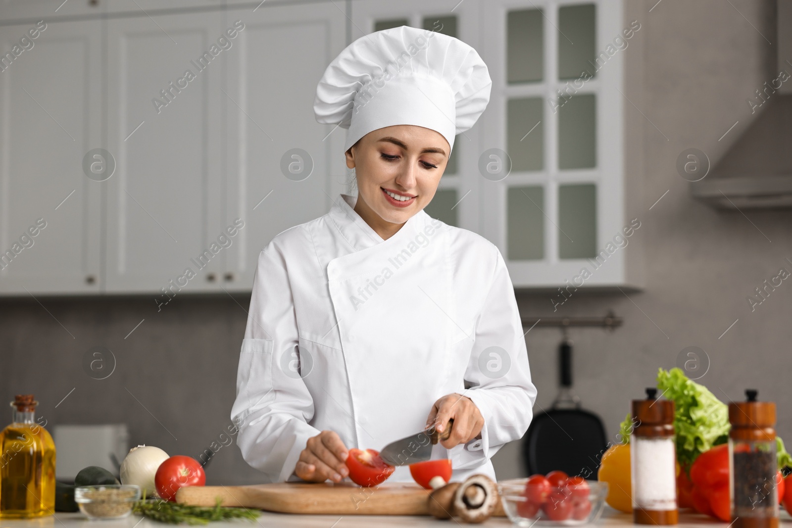 Photo of Professional chef cutting tomato at table in kitchen