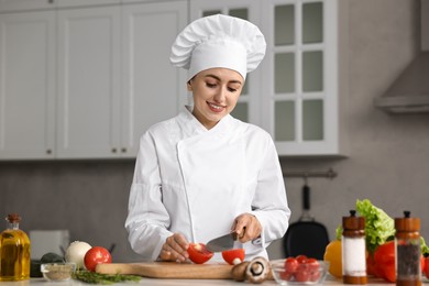 Professional chef cutting tomato at table in kitchen