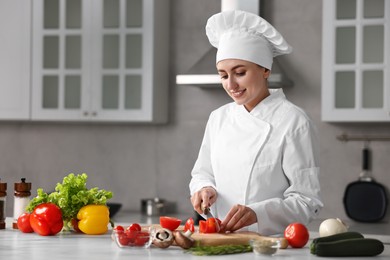 Photo of Professional chef cutting tomato at table in kitchen