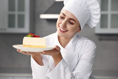 Photo of Professional chef with piece of delicious cheesecake in kitchen