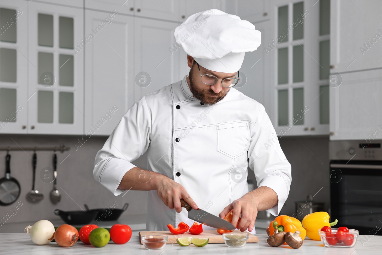 Photo of Professional chef cutting bell pepper at table in kitchen