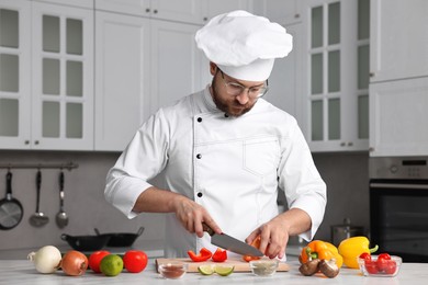 Professional chef cutting bell pepper at table in kitchen