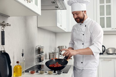 Photo of Professional chef adding salt into frying pan in kitchen