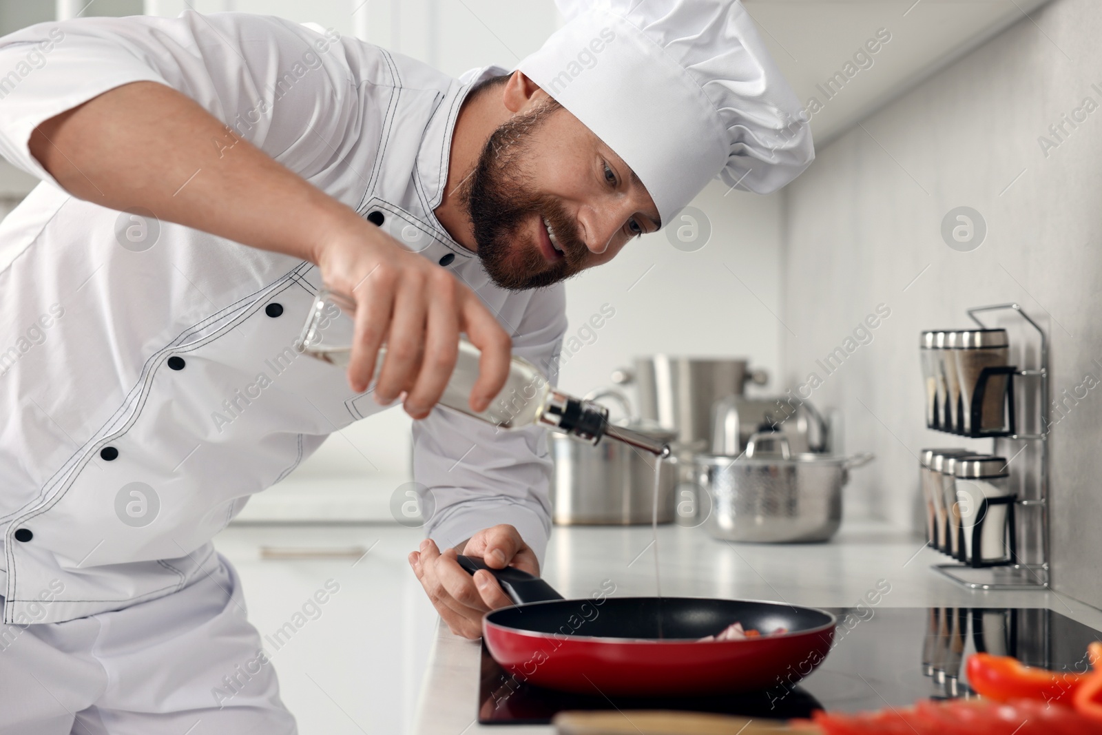 Photo of Professional chef pouring oil into frying pan in kitchen