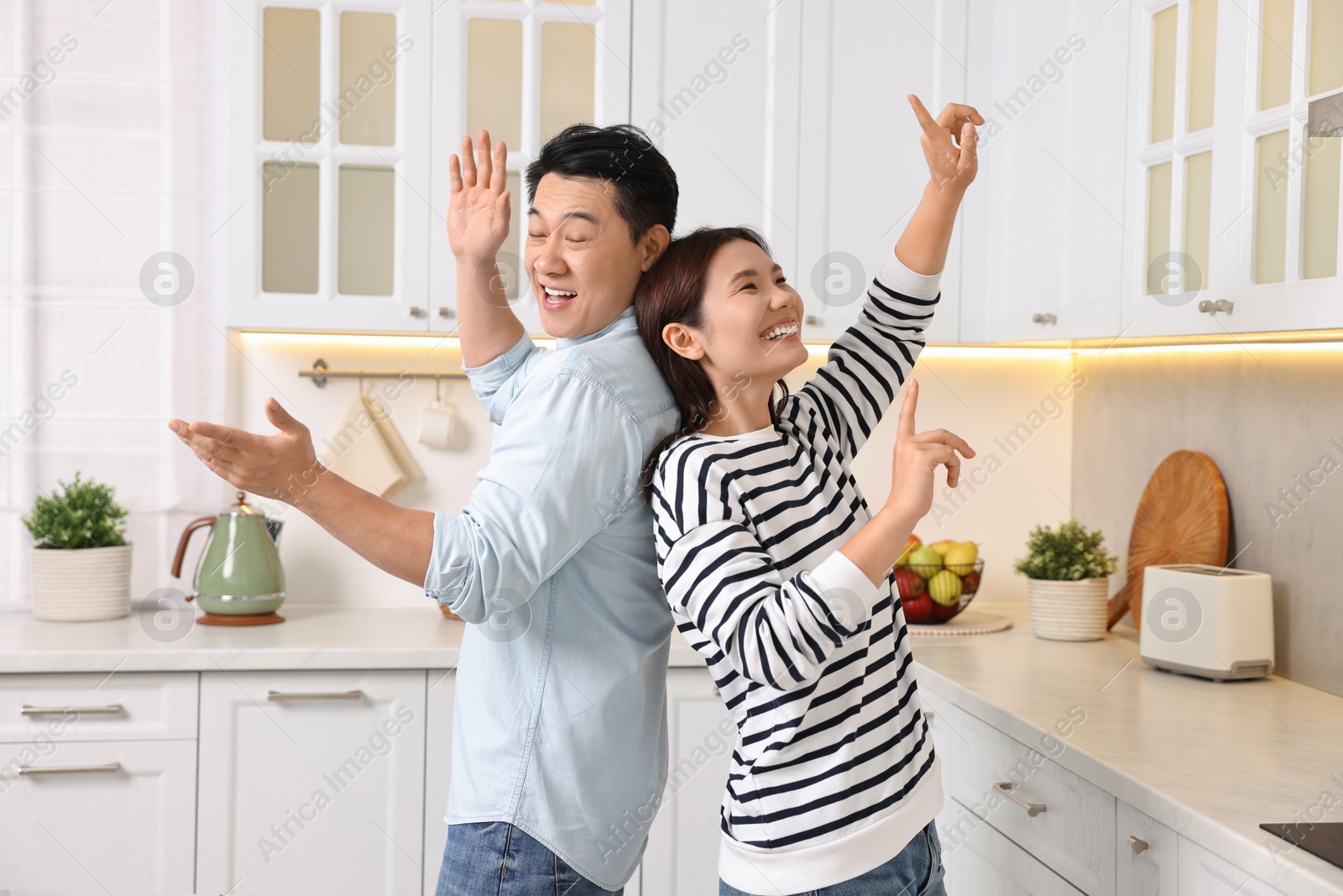 Photo of Happy lovely couple dancing together in kitchen