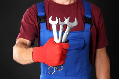 Photo of Auto mechanic with wrenches on black background, closeup