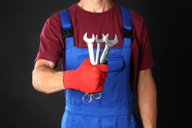 Photo of Auto mechanic with wrenches on black background, closeup