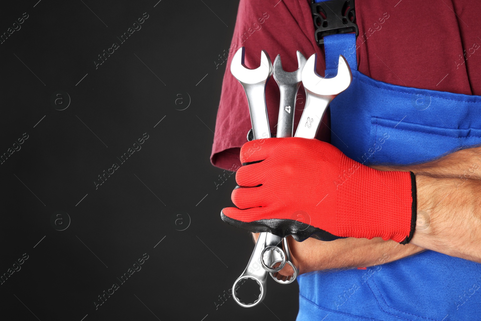 Photo of Auto mechanic with wrenches on black background, closeup. Space for text