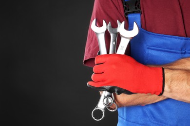 Auto mechanic with wrenches on black background, closeup. Space for text