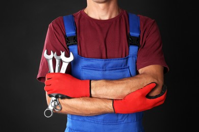 Auto mechanic with wrenches on black background, closeup