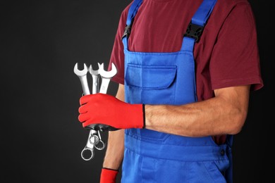 Photo of Auto mechanic with wrenches on black background, closeup. Space for text