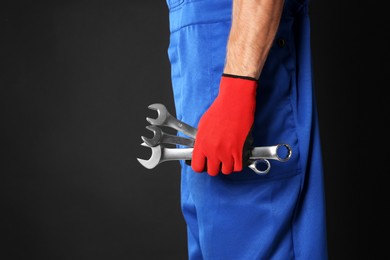 Photo of Auto mechanic with wrenches on black background, closeup. Space for text