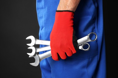 Photo of Auto mechanic with wrenches on black background, closeup