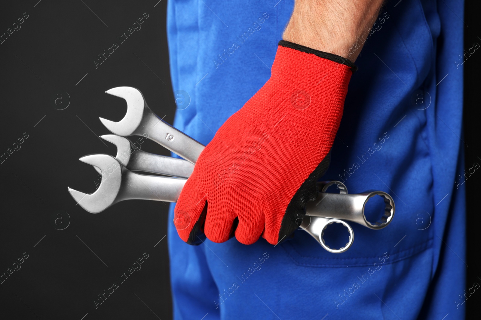 Photo of Auto mechanic with wrenches on black background, closeup