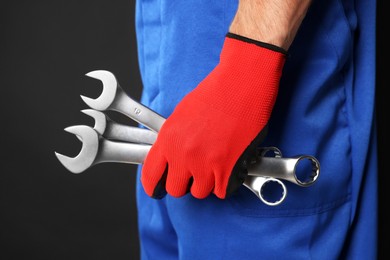 Auto mechanic with wrenches on black background, closeup