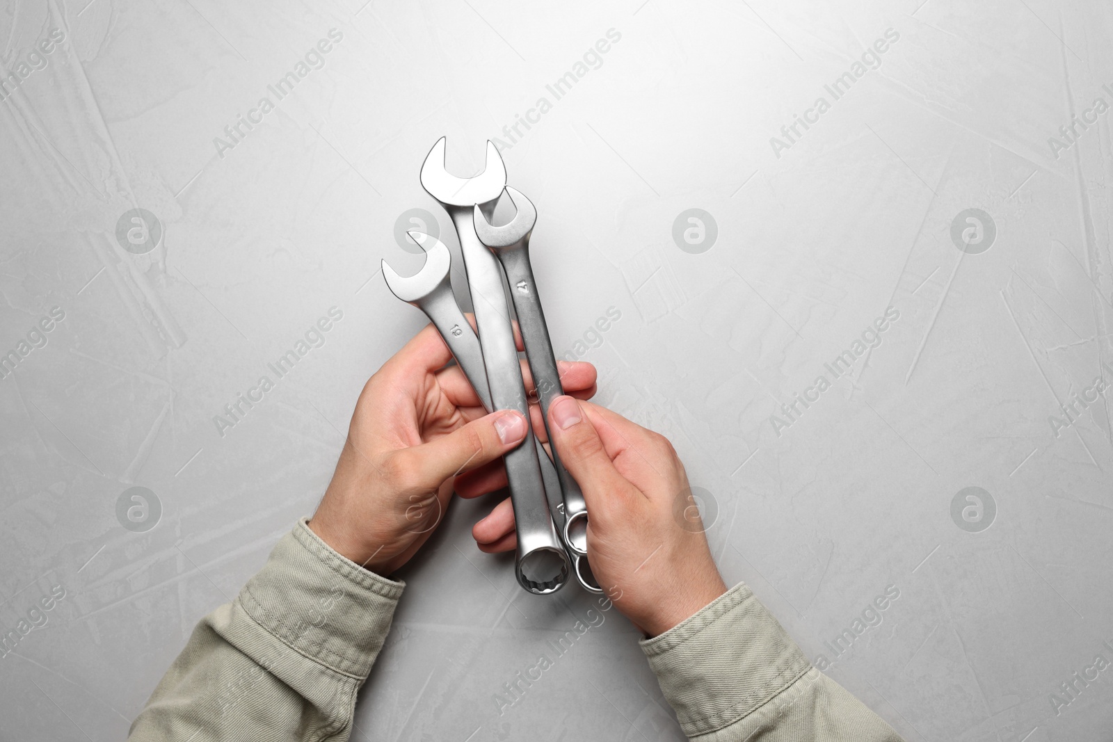 Photo of Auto mechanic with wrenches at light grey textured table, top view