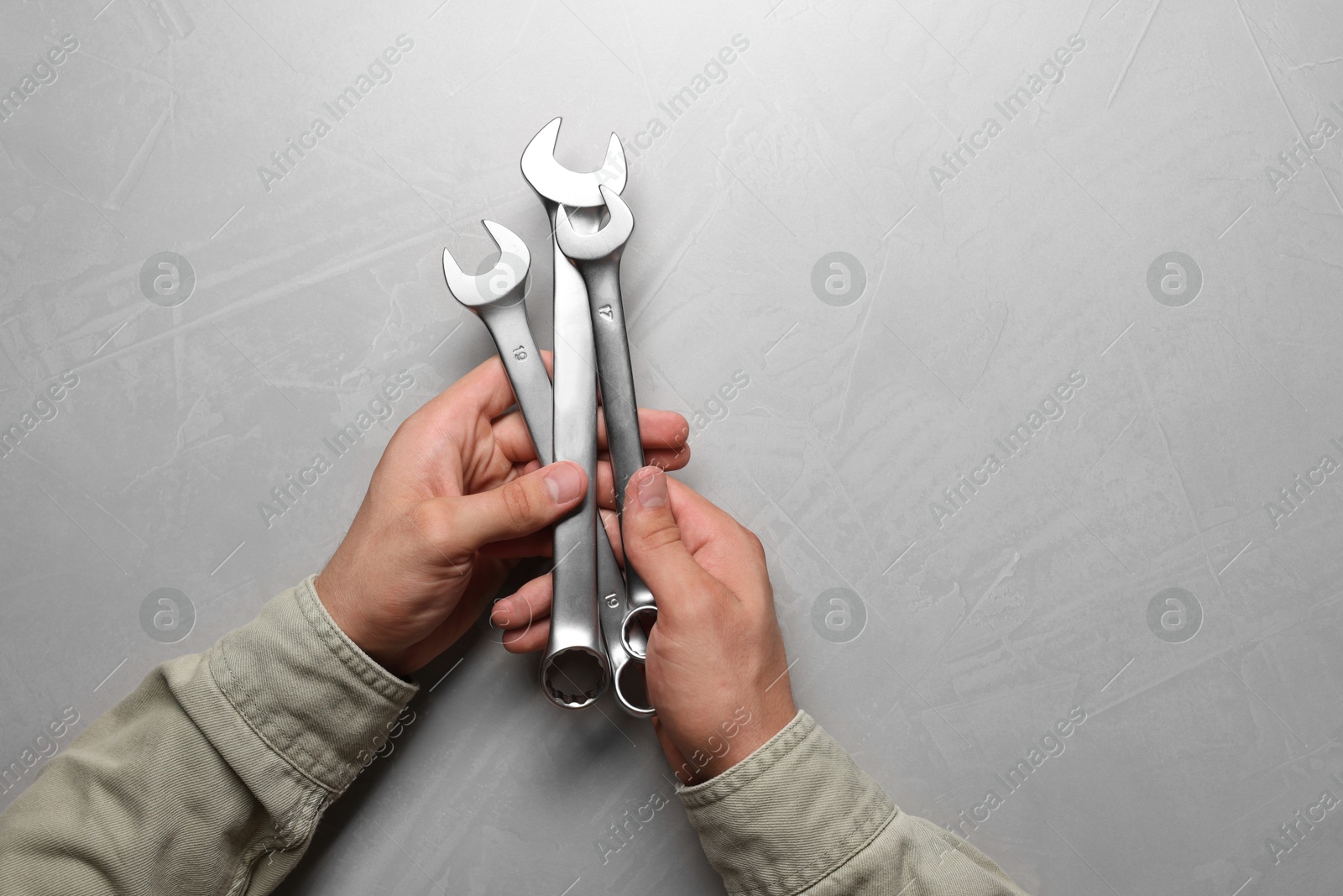 Photo of Auto mechanic with wrenches at light grey textured table, top view. Space for text