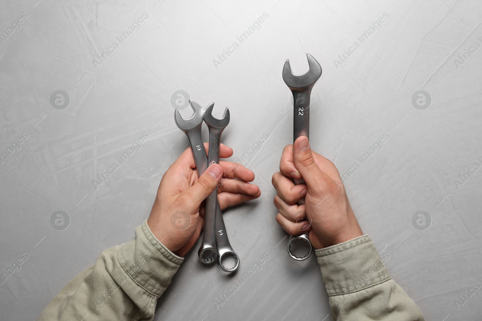 Photo of Auto mechanic with wrenches at light grey textured table, top view