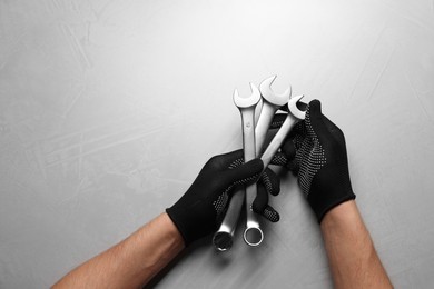 Photo of Auto mechanic with wrenches at light grey textured table, top view