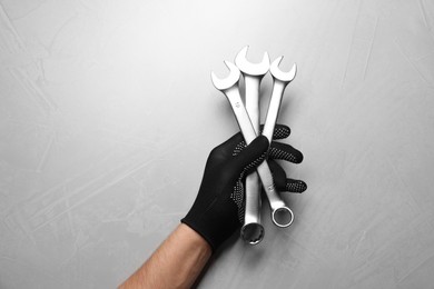 Auto mechanic with wrenches at light grey textured table, top view