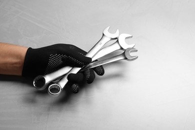 Photo of Auto mechanic with wrenches at light grey textured table, closeup