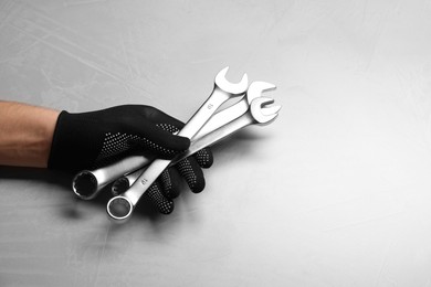 Photo of Auto mechanic with wrenches at light grey textured table, closeup