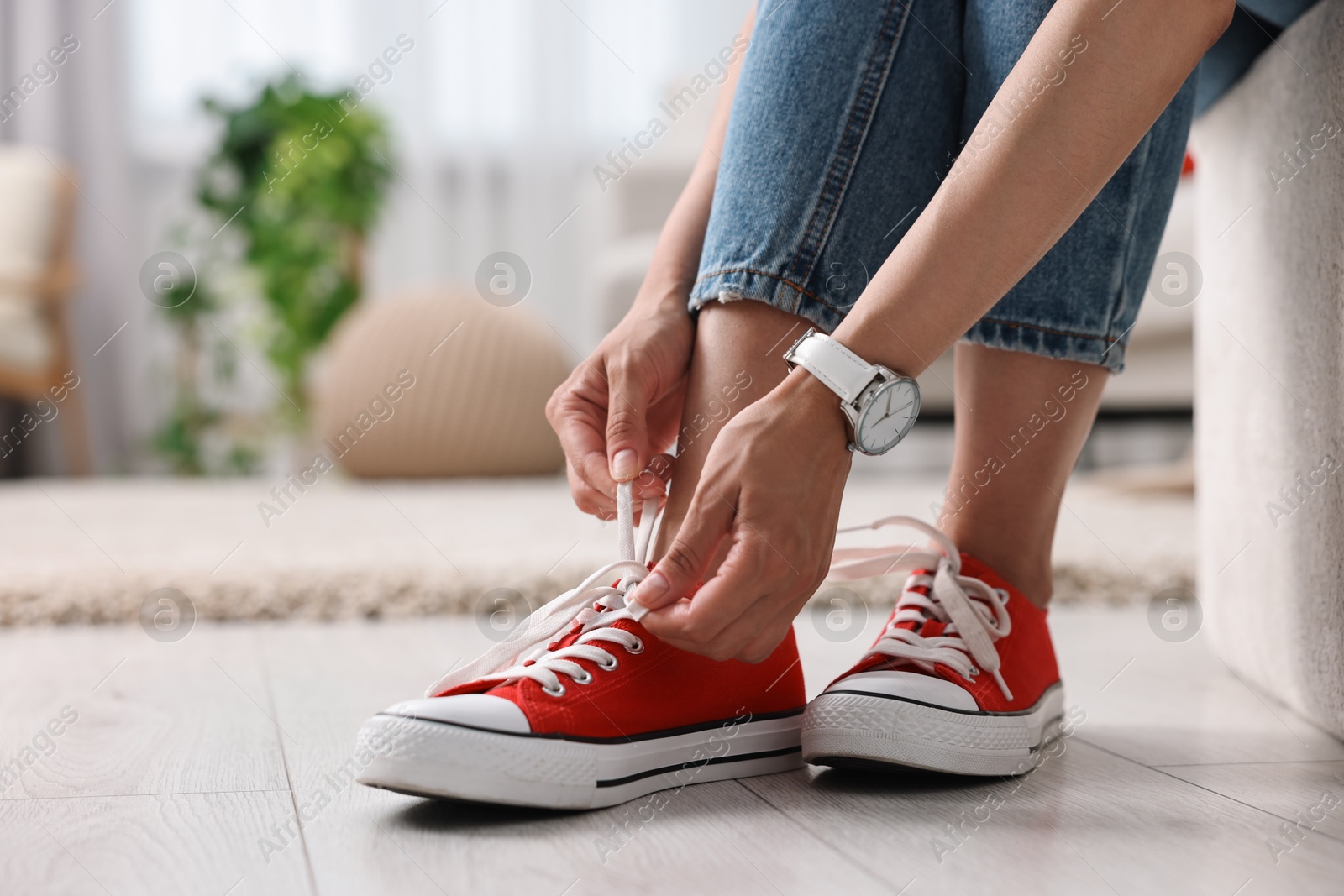 Photo of Woman tying shoelace of red sneaker indoors, closeup. Space for text