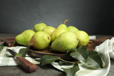 Photo of Many fresh ripe pears, green leaves and knife on grey table