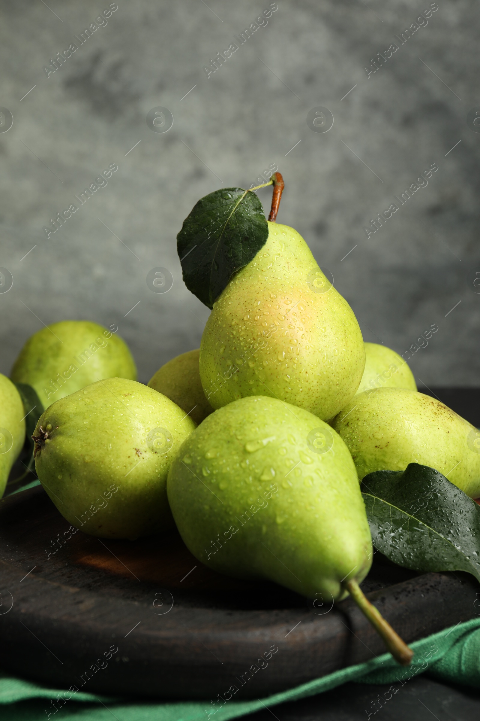 Photo of Many fresh ripe pears and green leaves on table, closeup