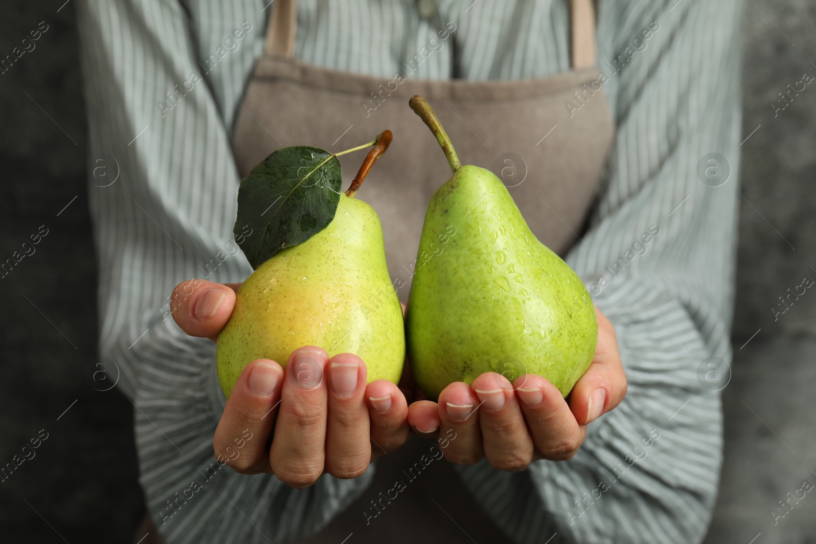 Photo of Woman with ripe pears near grey wall, closeup