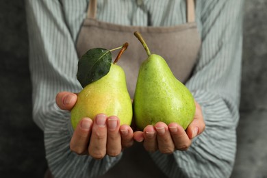 Photo of Woman with ripe pears near grey wall, closeup