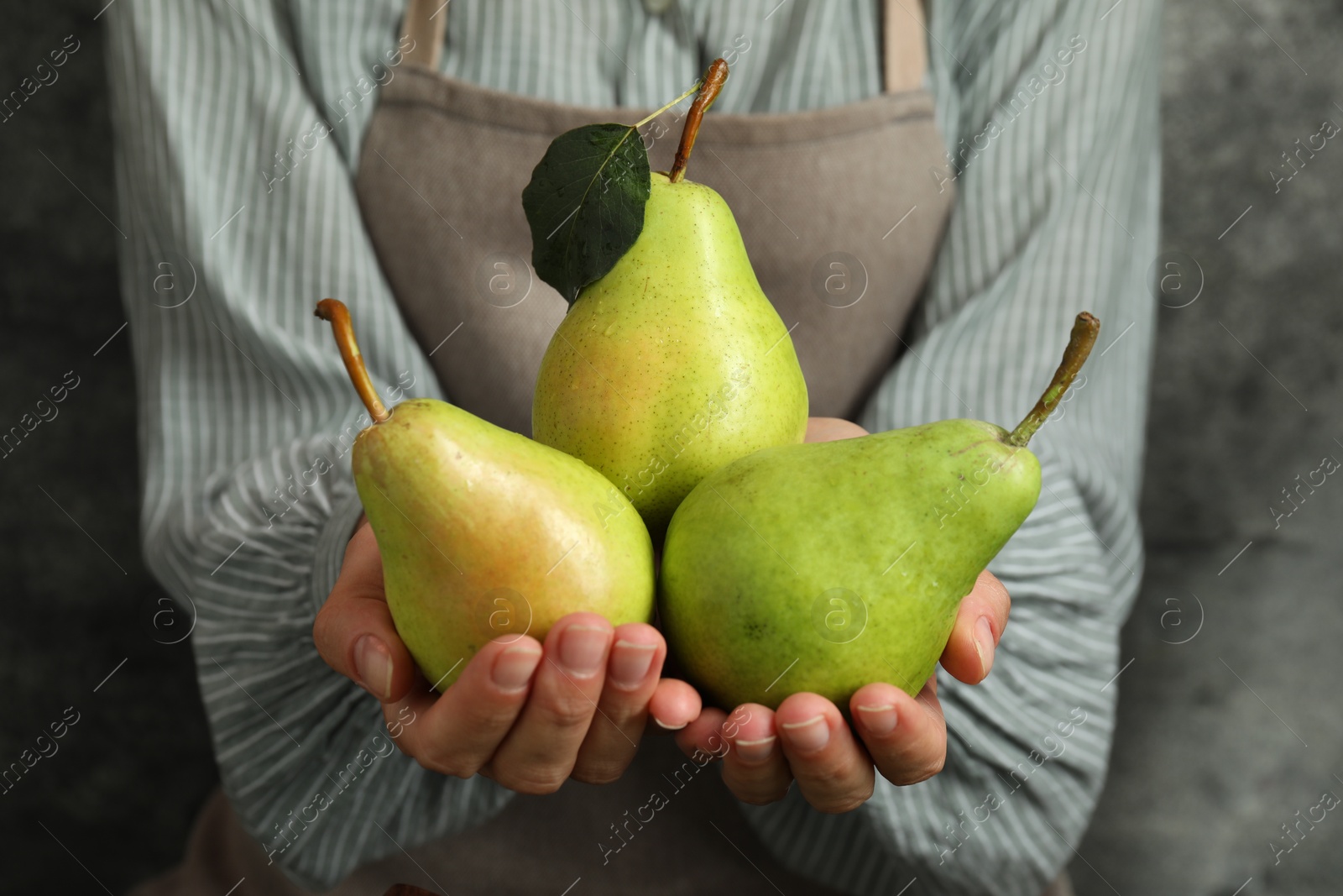 Photo of Woman with ripe pears near grey wall, closeup