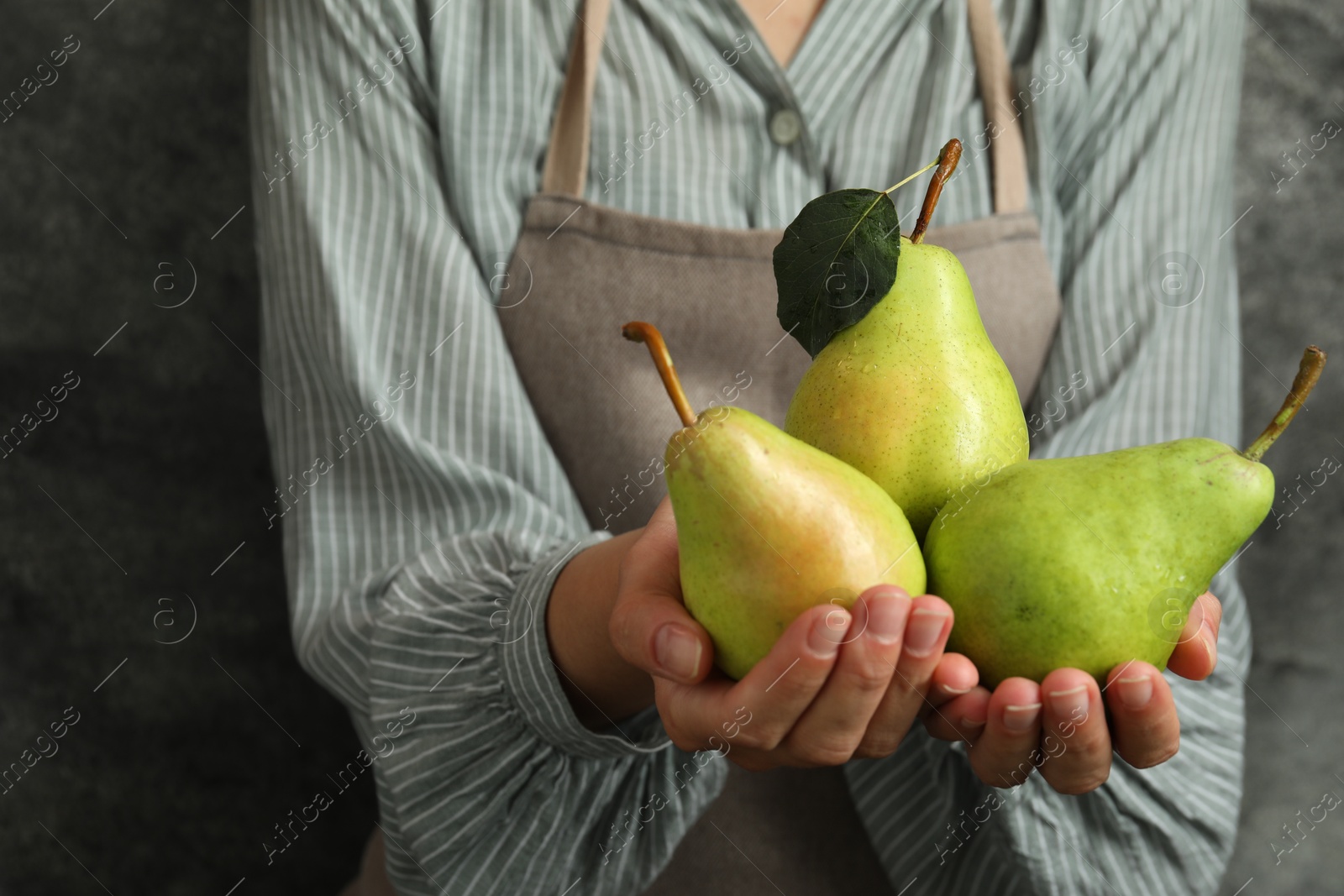 Photo of Woman with ripe pears near grey wall, closeup