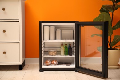 Mini refrigerator with different drinks and snacks indoors