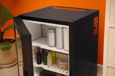 Mini refrigerator with different drinks and snacks indoors